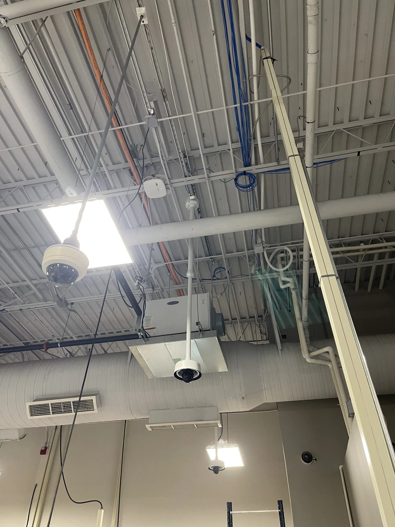 Dome surveillance cameras on suspended mounts in a commercial facility.